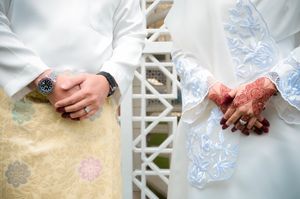 Close-up of a couple in traditional wedding attire with henna art and accessories.