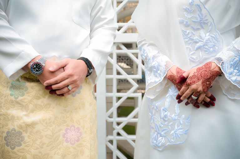 Close-up of a couple in traditional wedding attire with henna art and accessories.