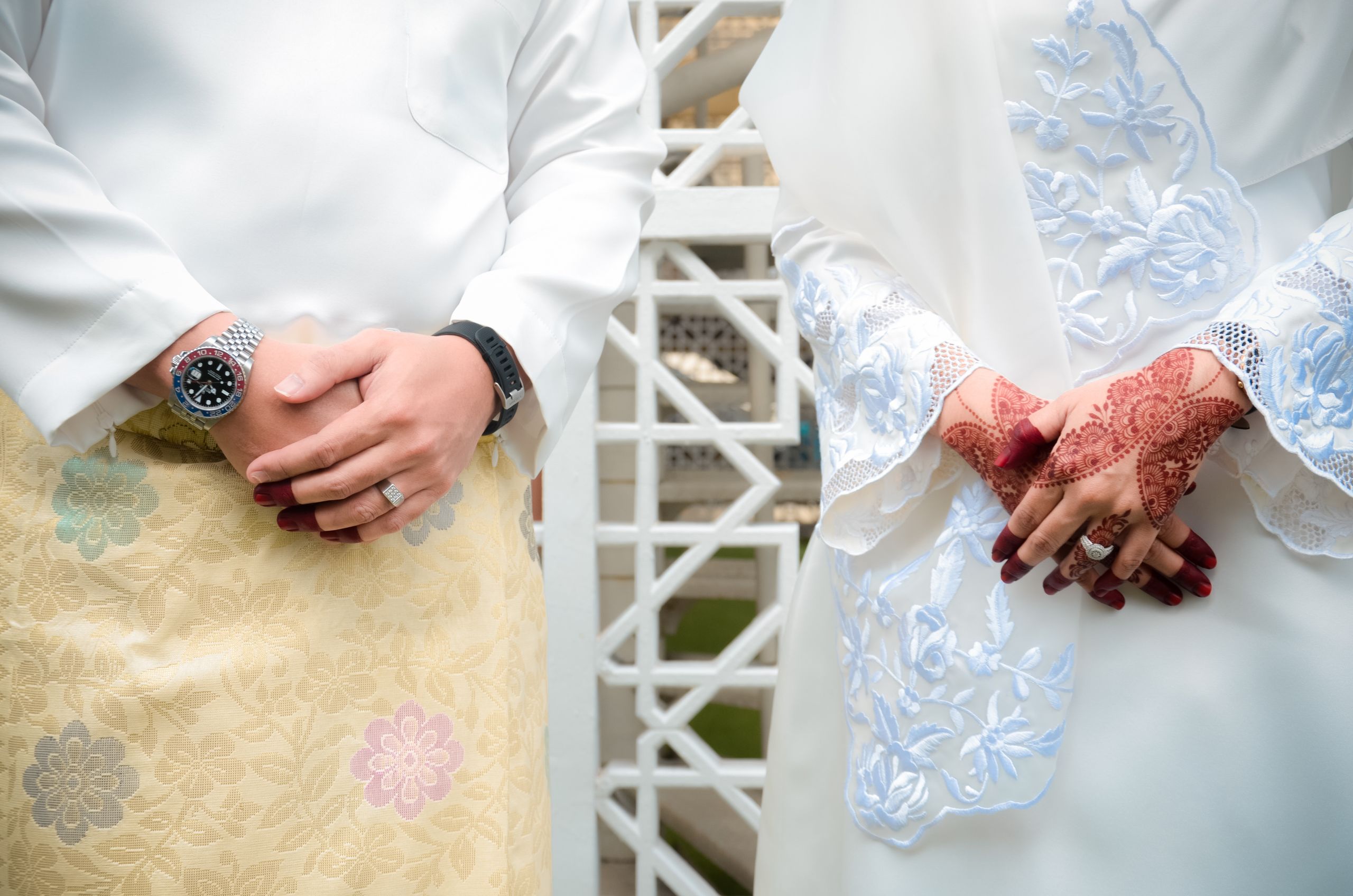 Close-up of a couple in traditional wedding attire with henna art and accessories.